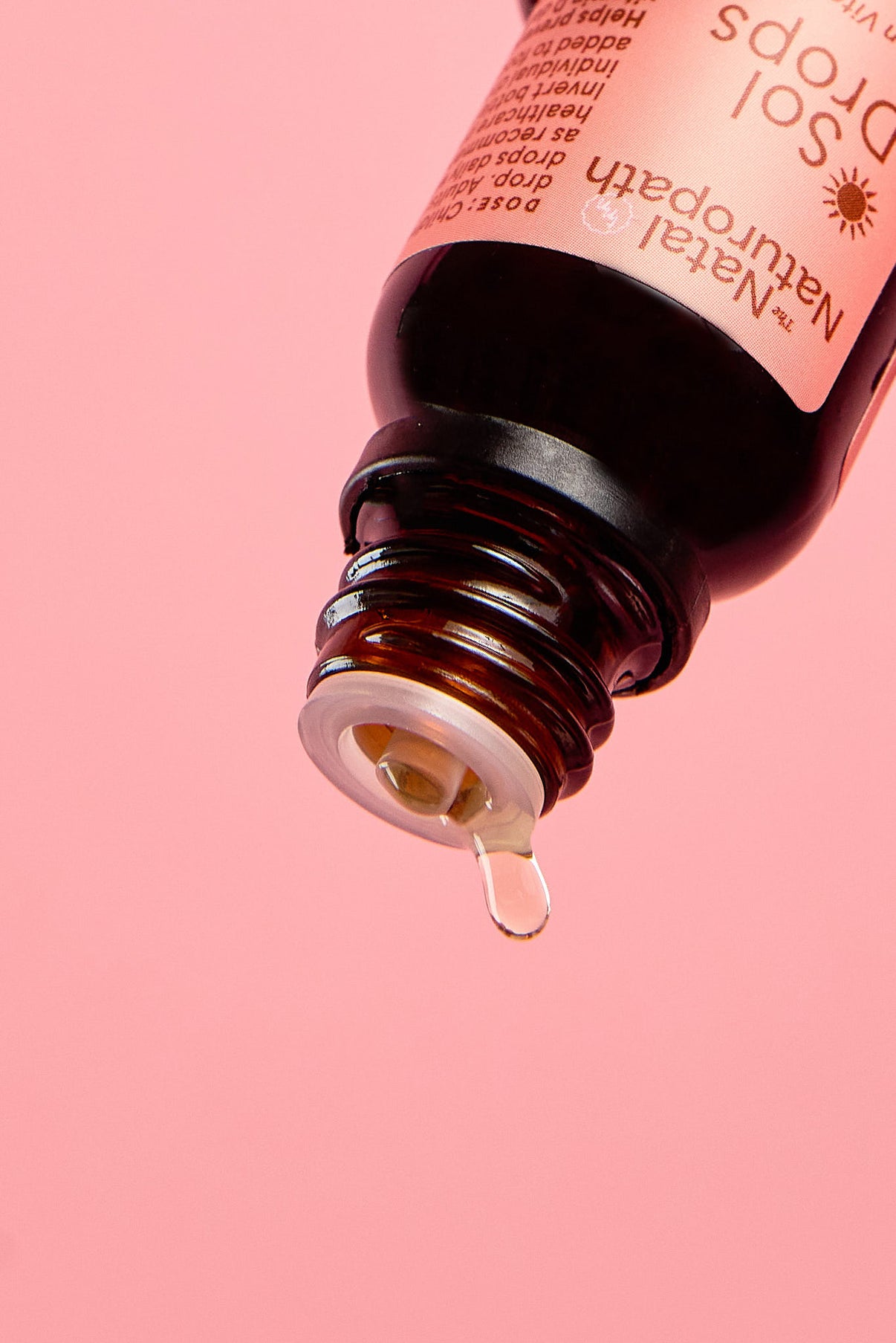 Bottle of Sol natural drops with a droplet on a pink background