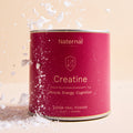 Red canister labeled 'Creatine' by Naternal on a beige background with white powder around it.