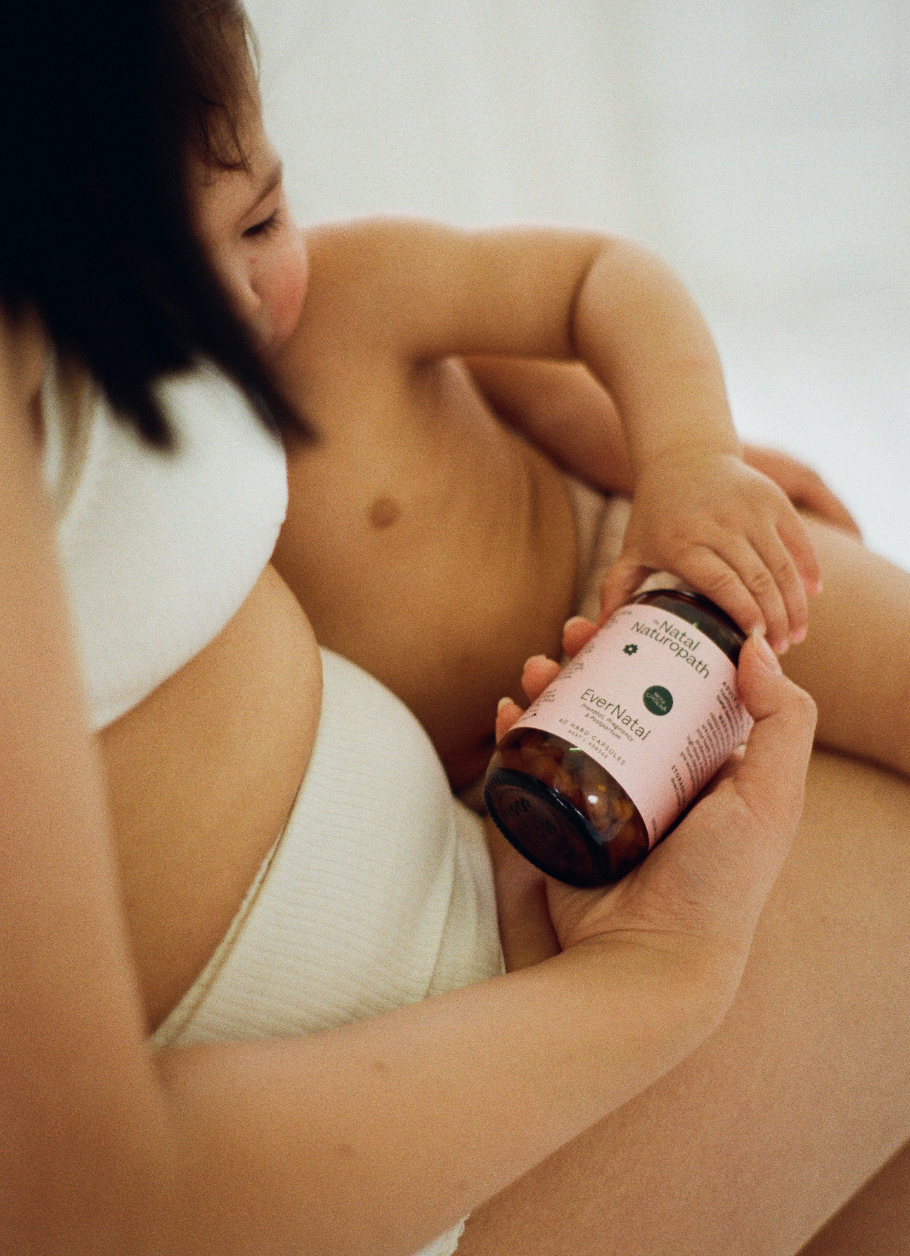 A close, intimate moment of a mother holding her child while gently holding a bottle of Naternal Vitamins EverNatal supplement. The mother and child’s relaxed, nurturing pose highlights the product’s focus on maternal and postpartum wellness.