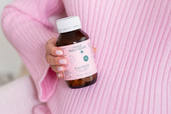 Close-up of a woman in a cosy pink sweater holding a bottle of Naternal Vitamins EverNatal, a prenatal, pregnancy, and postpartum supplement. The soft, nurturing setting emphasises maternal care and wellness.